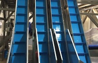 a conveyor belt in a factory with blue boxes on it